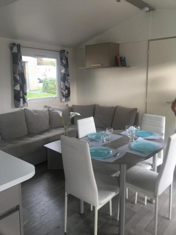 uma sala de jantar com uma mesa e cadeiras e um sofá em Mobil Home 257 M et Mme COLAS em Litteau