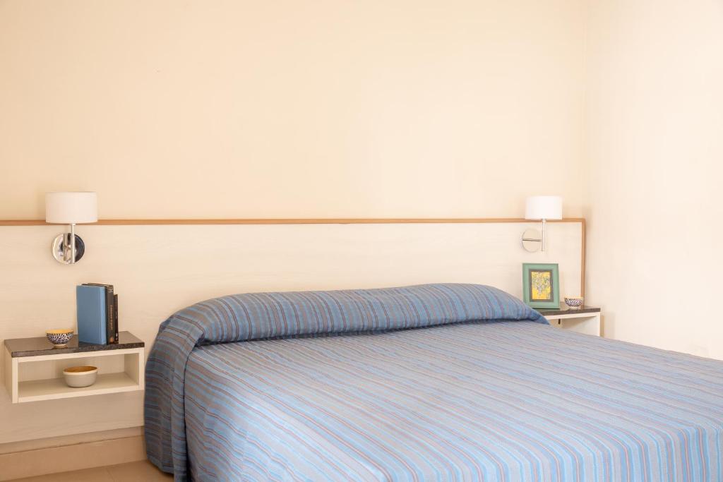 een slaapkamer met een bed met een blauw gestreepte deken bij Happy Sea Home - monolocale sul mare con piscina in Albinia