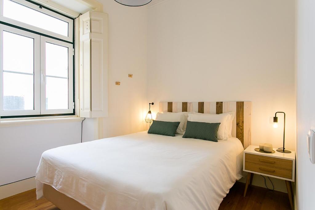 - une chambre blanche avec un grand lit et une fenêtre dans l'établissement LovelyStay - Cozy 3BDR Apartment in Estrela, à Lisbonne