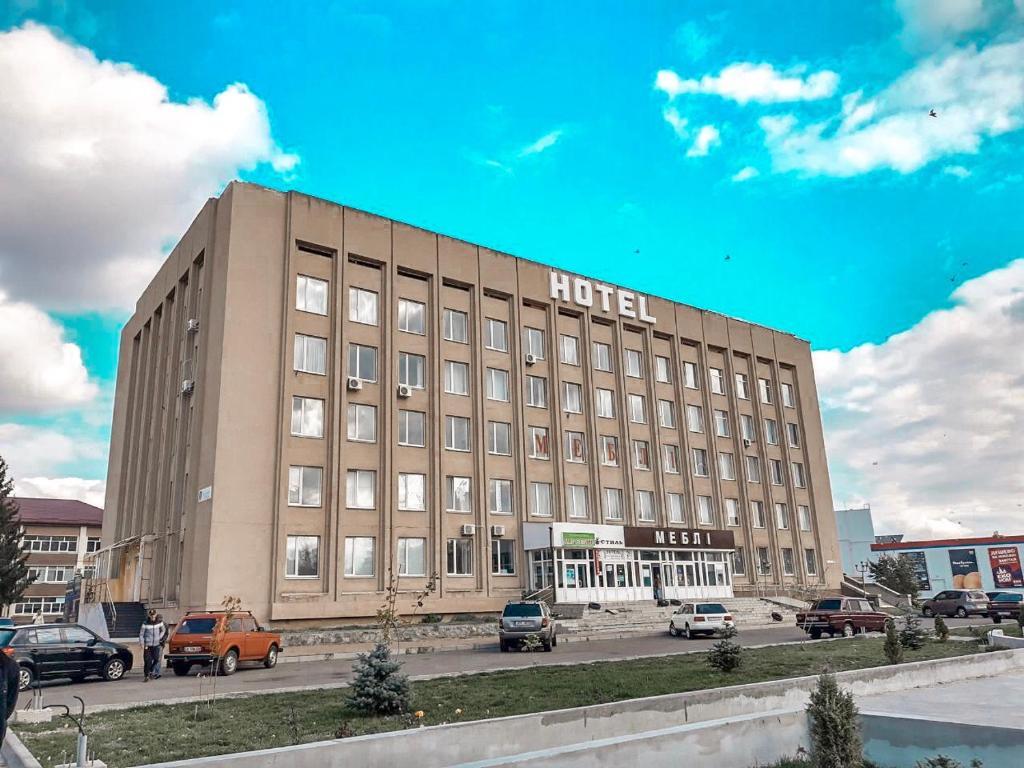 un edificio de hotel con coches aparcados en un aparcamiento en Отель Меридиан en Zolotonosha