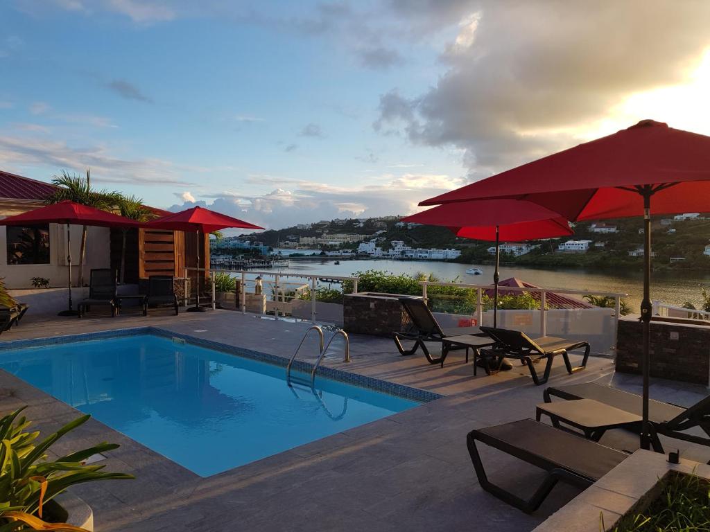 una piscina con muebles de exterior y sombrillas en Les Balcons d'Oyster Pond, en Saint Martin