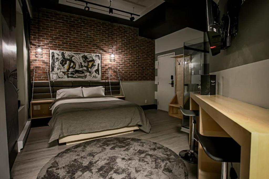 a bedroom with a bed and a brick wall at La Suite Hébergements in Shawinigan