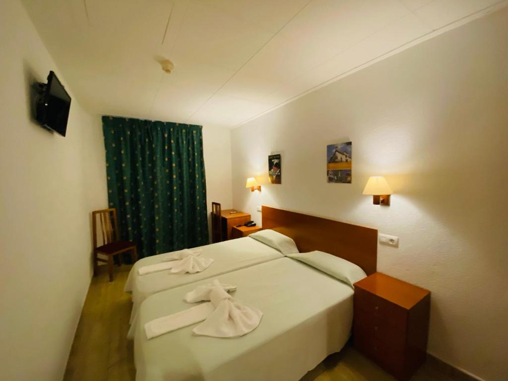Habitación de hotel con cama y cortina verde en Hotel Mitus, en Canet de Mar