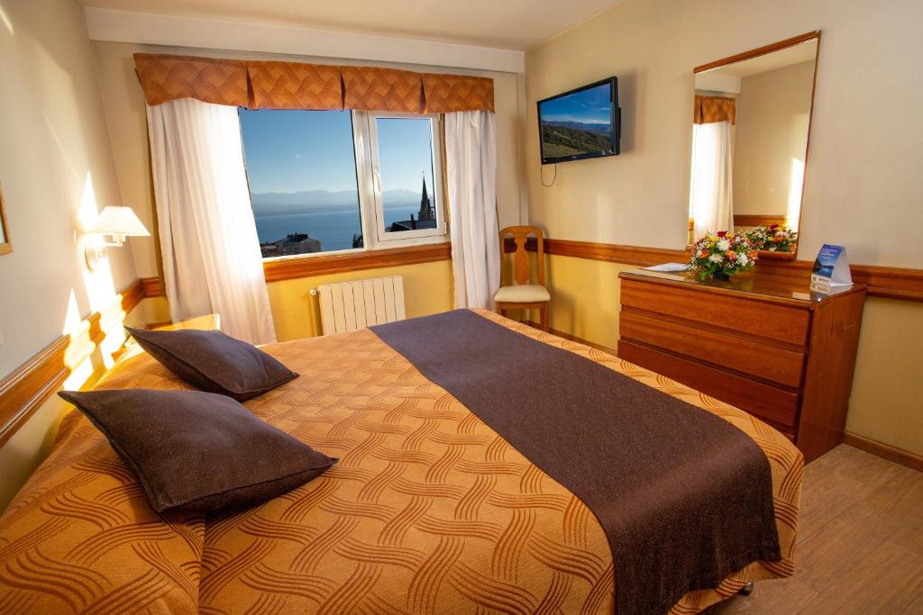 a bedroom with a bed and a dresser and a window at Patagonia Sur Hotel in San Carlos de Bariloche