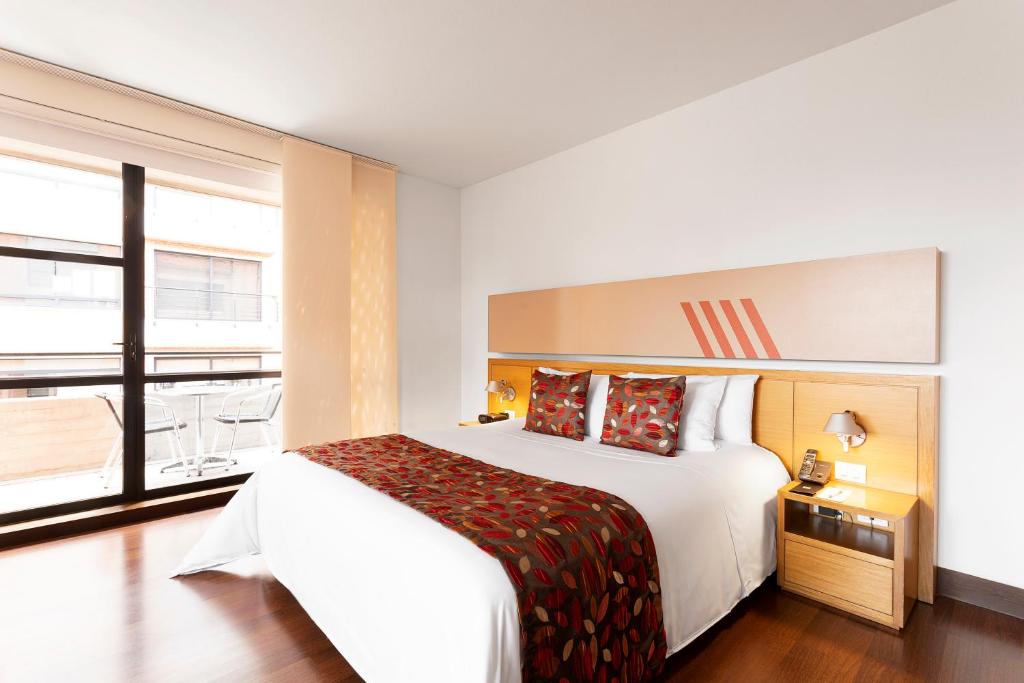 ボゴタにあるHotel bh La Quintaのベッドと大きな窓があるホテルの部屋