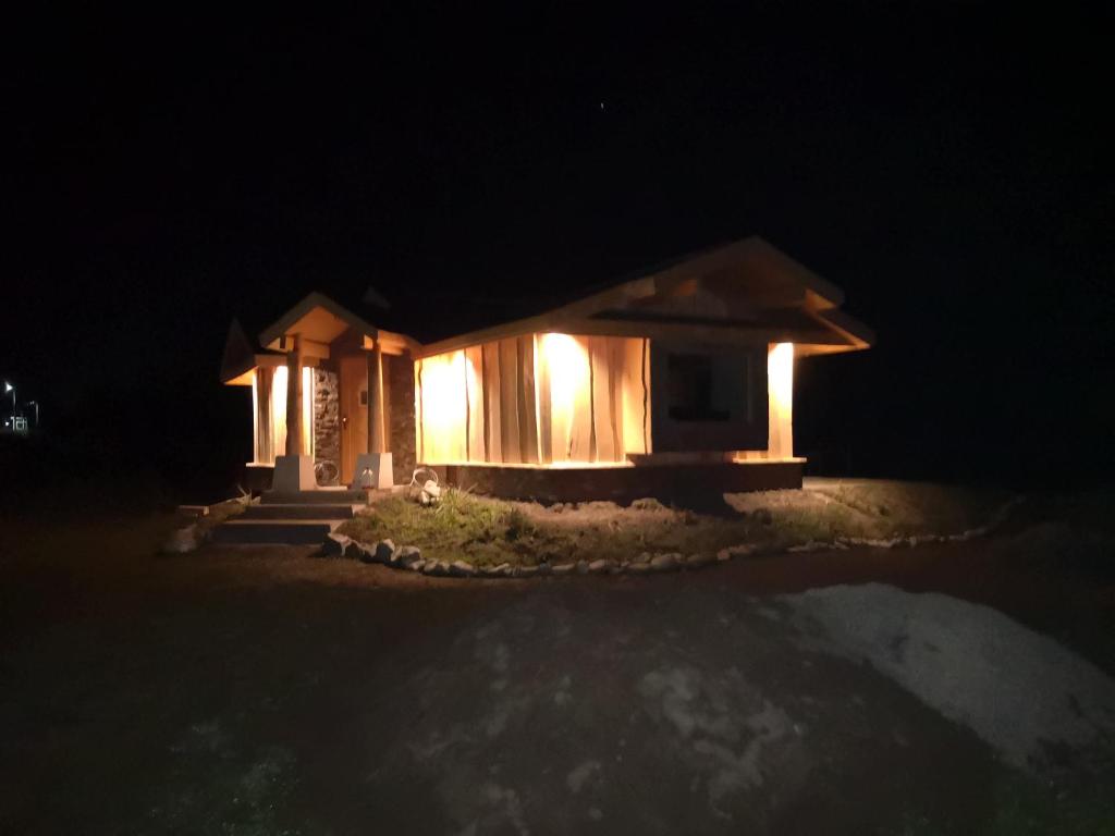 une petite maison avec des lumières allumées la nuit dans l'établissement Alpin Lodge, à Azuga