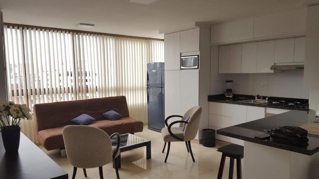 a kitchen and a living room with a couch and chairs at Apartosuites cerca del Boulevar de Sabana Grande y la Av. Solano in Caracas