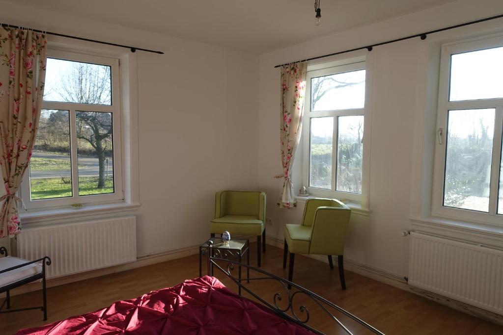 Schlafzimmer mit 2 Stühlen, einem Bett und Fenstern in der Unterkunft Hotel Alpenblick in Todenbüttel
