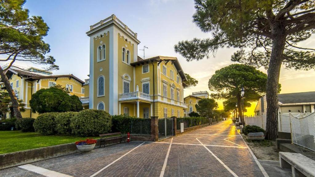 ein gelbes Haus mit einem Uhrturm auf einer Straße in der Unterkunft Residence Villa Marina in Grado