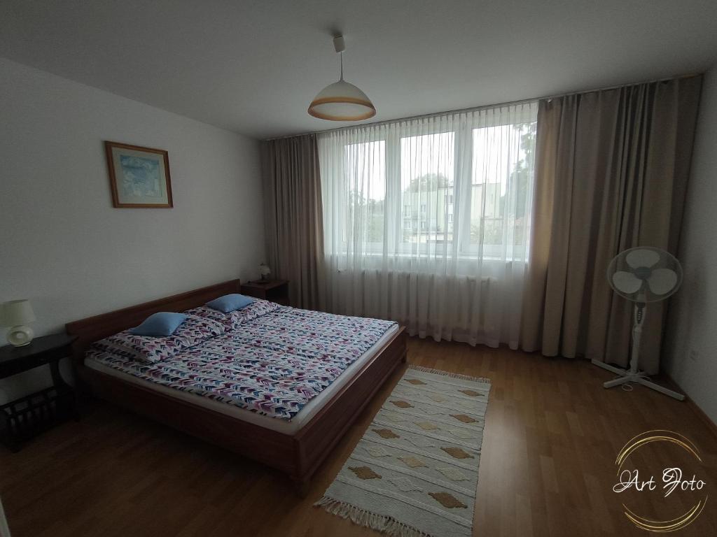 a bedroom with a bed and a large window at Apartament – 3 pokojowe dwupoziomowe mieszkanie z ogrodem in Krokowa