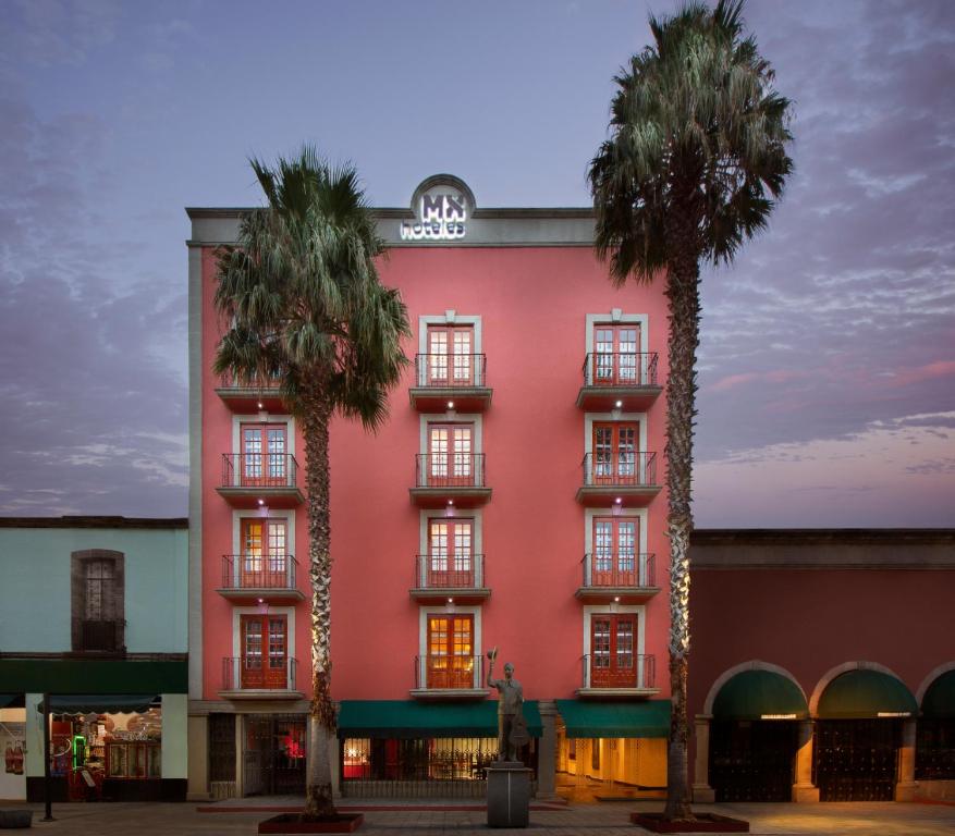 un edificio rosa con dos palmeras delante en Hotel MX garibaldi, en Ciudad de México