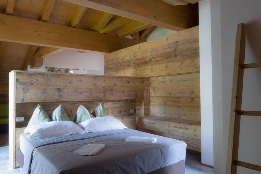 1 dormitorio con 1 cama grande y pared de madera en Pigala Al Drit, en Rivamonte
