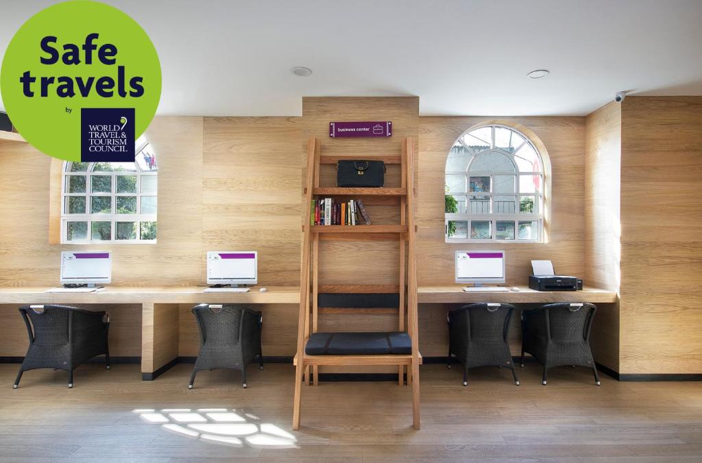 A bright shared work area with three computer stations, chairs, bookshelves, and a printer.