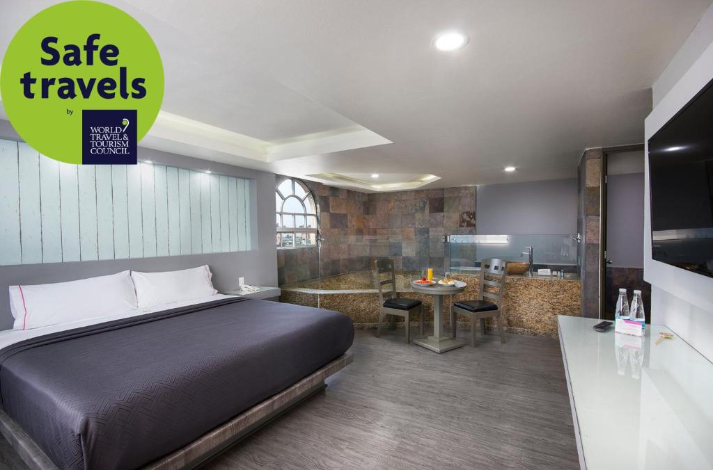 A large double room combining a bed, dining nook, kitchenette-style counter, and wall-mounted TV.