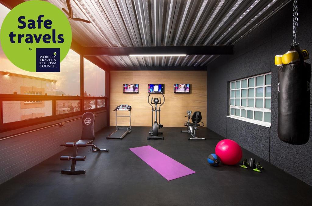 A compact gym with cardio machines, weights, a yoga mat, and a hanging punching bag.