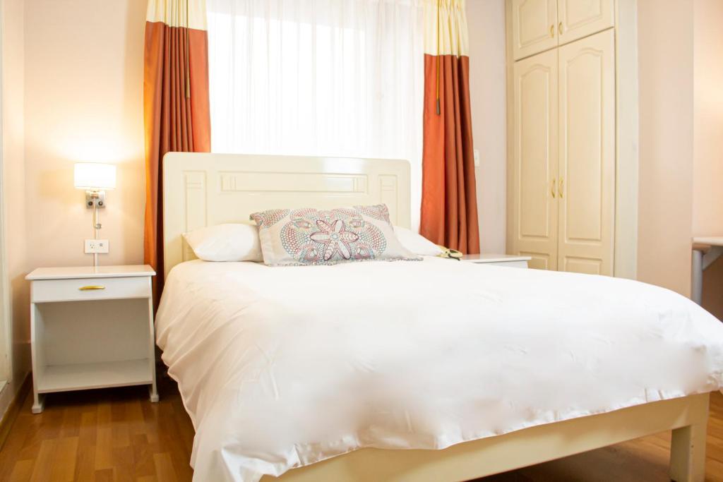 1 dormitorio con cama blanca y ventana en Hotel Sandmelis, en Quito