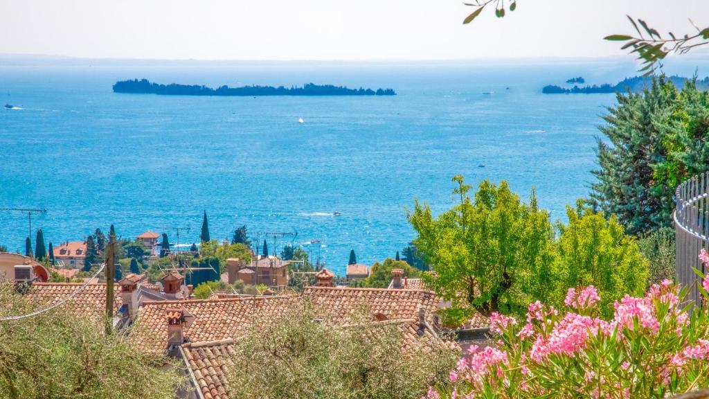 a view of the ocean from a hill with flowers at La cà dei ulif in Gardone Riviera