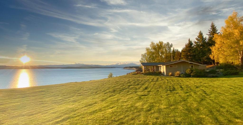 dom na wzgórzu obok zbiornika wodnego w obiekcie Pukaki Lakeside Getaway NZ w mieście Jezioro Pukaki