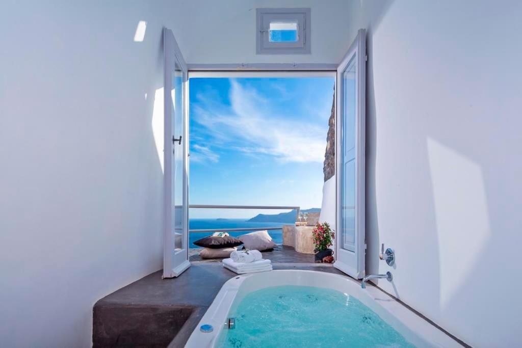a bathroom with a bath tub and an open door at Luxury Santorini Villa Secret Escape Villa Private Pool Sea Caldera View 2 BDR Oia in Thólos