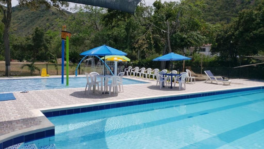 uma piscina com cadeiras e guarda-sóis e uma mesa e cadeiras em Club campestre el Peñón de Apulo em Apulo