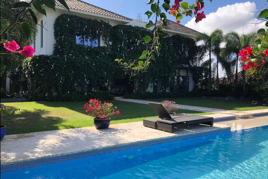 a house with a lap top on a bench next to a swimming pool at Casa Tropical con Hermosos Atardeceres Caribeños in Santiago de los Caballeros