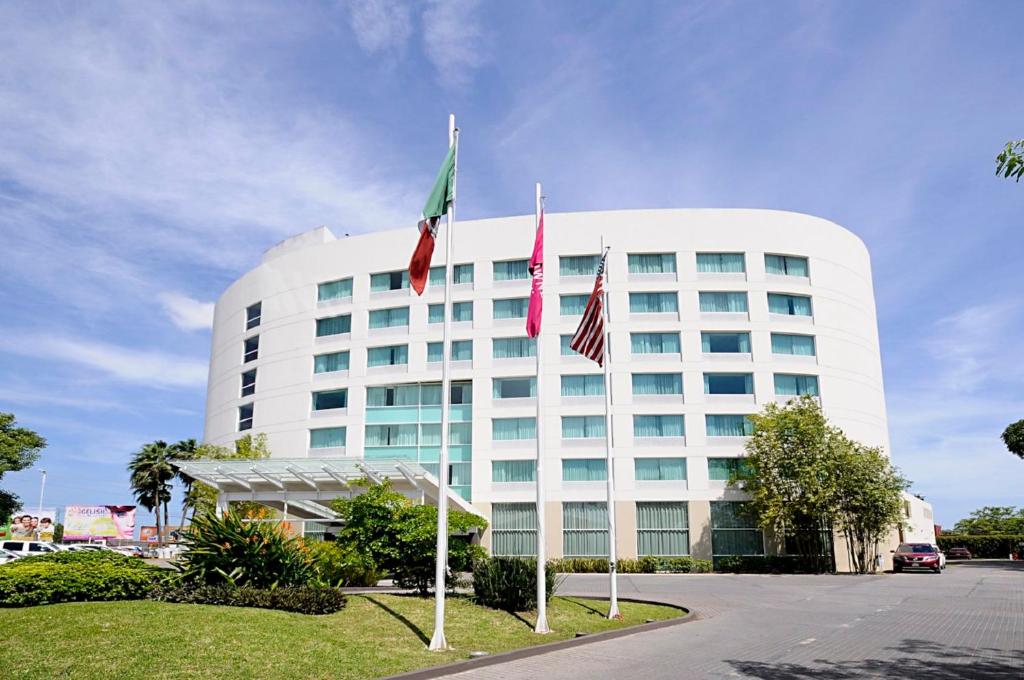 un edificio blanco con dos banderas delante en Crowne Plaza Villahermosa, an IHG Hotel, en Villahermosa