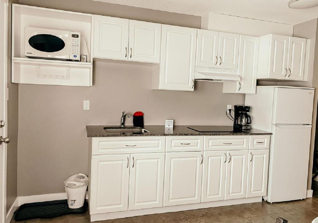 a white kitchen with white cabinets and a microwave at Hinton Highway Inn in Hinton