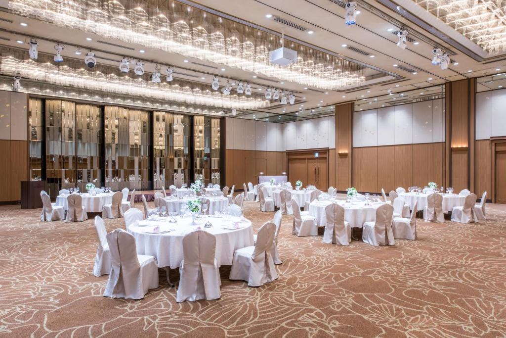 a banquet hall with white tables and chairs and chandeliers at ANA Crowne Plaza Kanazawa by IHG in Kanazawa