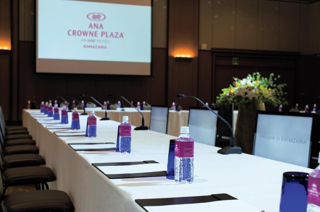 a long table with bottles of water on it in front of a screen at ANA Crowne Plaza Kanazawa by IHG in Kanazawa