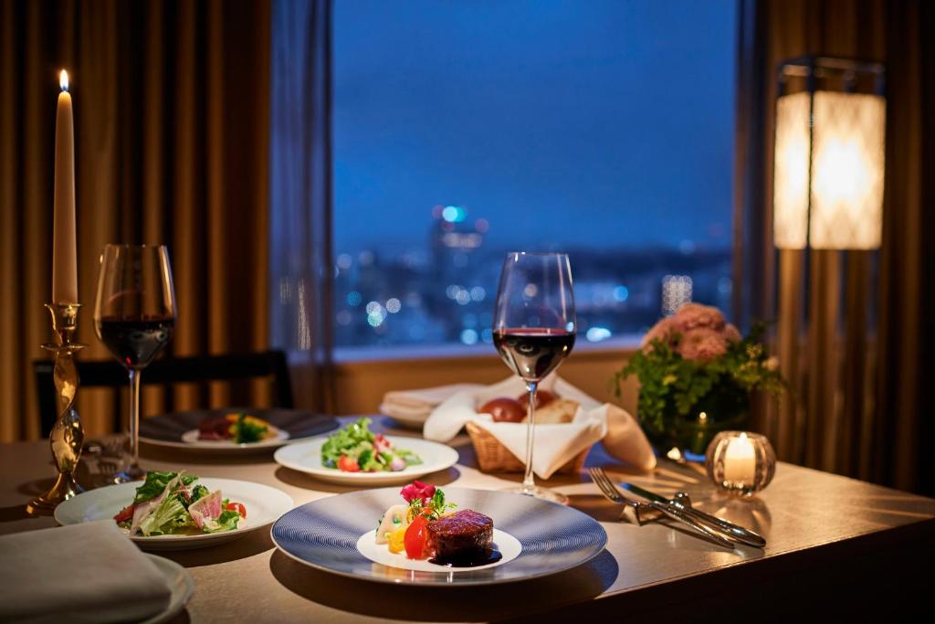 a table with plates of food and a glass of wine at ANA Crowne Plaza Kanazawa by IHG in Kanazawa