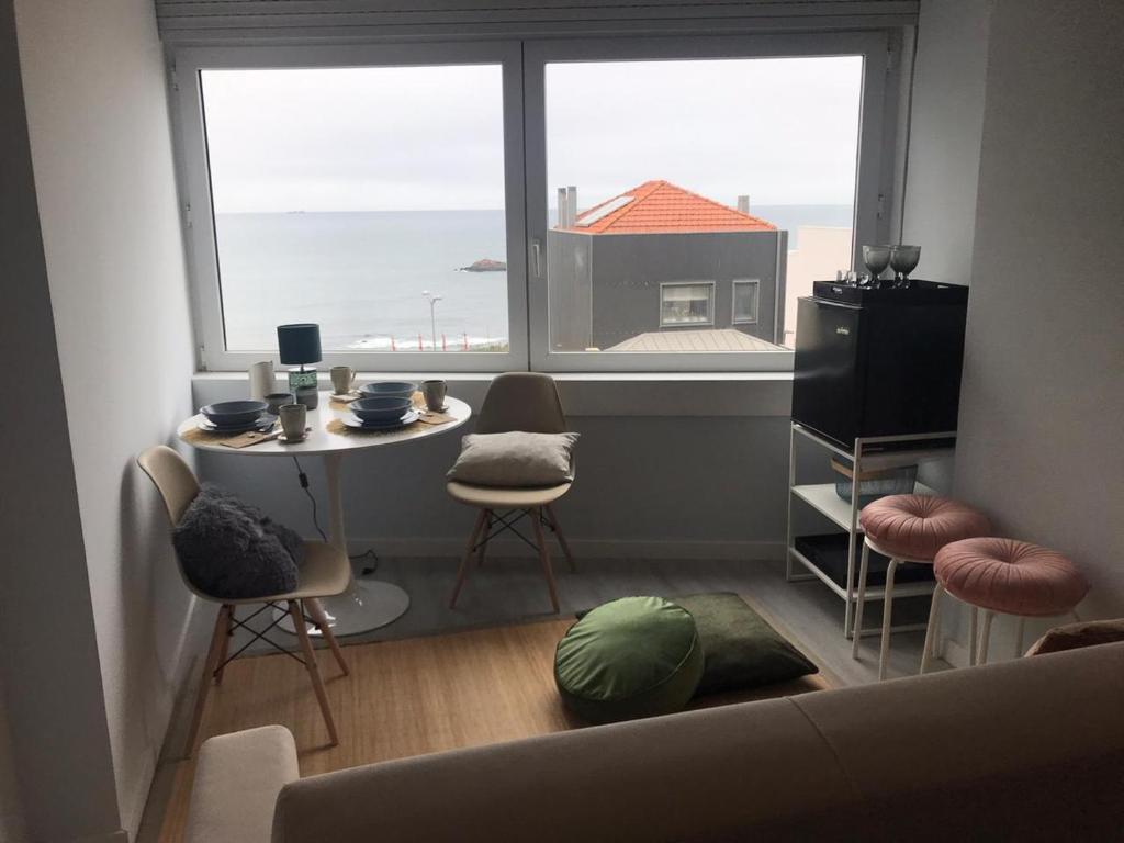 a living room with a table and chairs and a large window at Porto Beach Rooms in Porto
