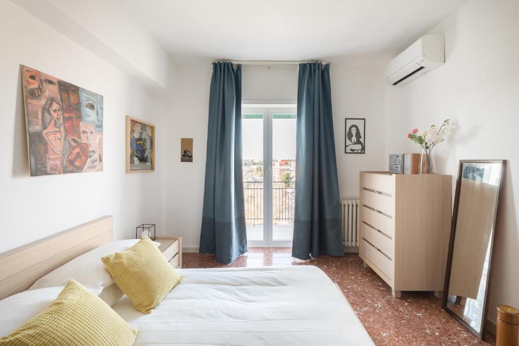 a bedroom with a bed and a window with blue curtains at Amoretti Apartment, 6 persone, 3 camere, 2 bagni, balcone, Wi-Fi, Metro B Monti Tiburtini in Rome