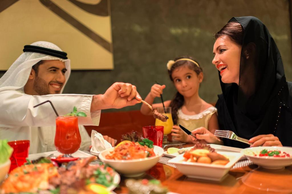 a man and a woman sitting at a table eating food at Crowne Plaza Yas Island by IHG in Abu Dhabi