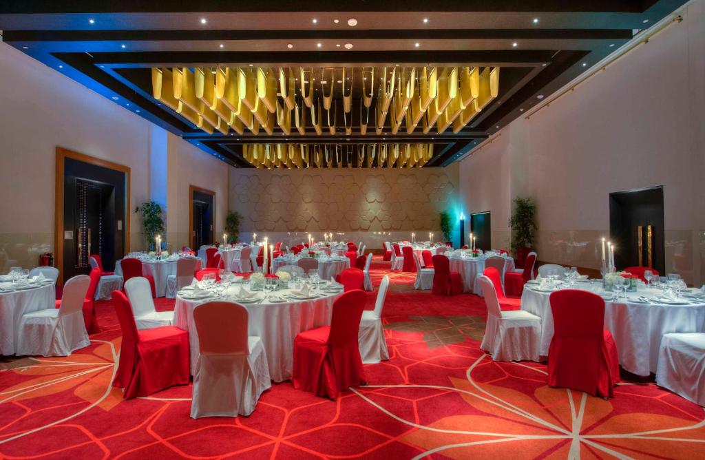 a banquet hall with white tables and red chairs at Crowne Plaza Yas Island by IHG in Abu Dhabi