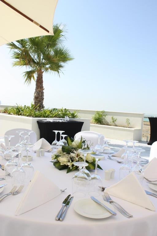 a table with white plates and silverware and a palm tree at Crowne Plaza Yas Island by IHG in Abu Dhabi