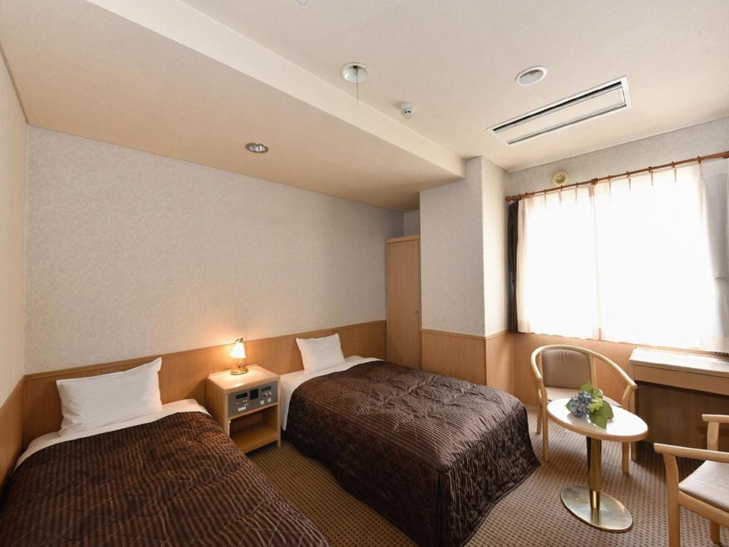 a hotel room with two beds and a window at Hotel Pearl City Sapporo in Sapporo