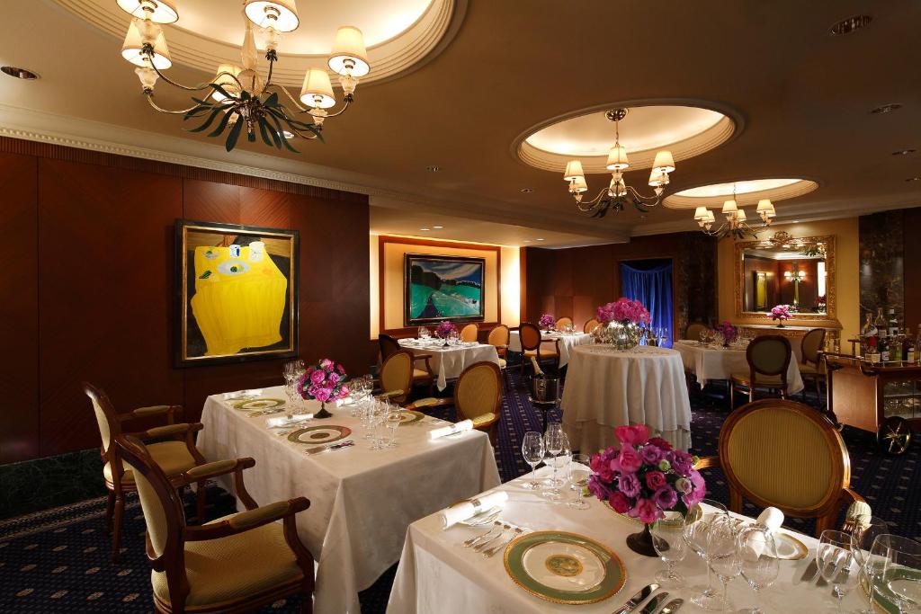a dining room with white tables and chairs with flowers on them at ANA Crowne Plaza Hotel Kyoto by IHG in Kyoto