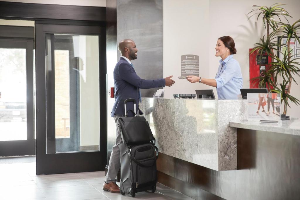 a man and a woman shaking hands at a counter at Staybridge Suites - Miami International Airport by IHG in Miami