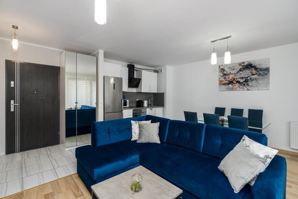 uma sala de estar com um sofá azul e uma cozinha em Sleepway Apartments - Strzelecka 29A-15 em Poznań