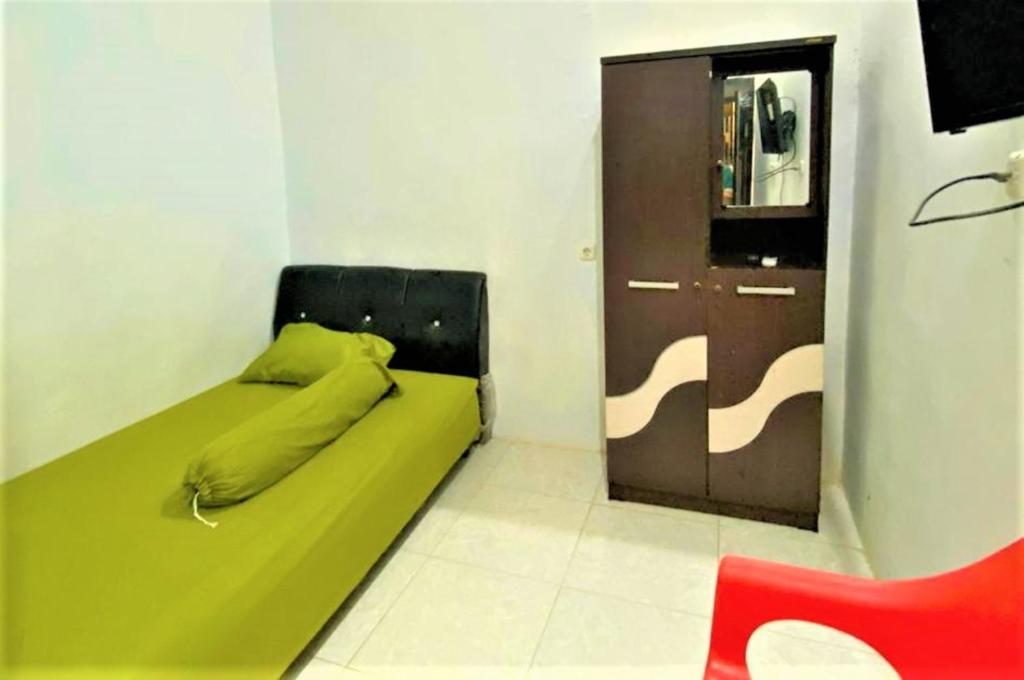 - une petite chambre avec un lit vert et une porte dans l'établissement Radja Guest House, à Balangberu