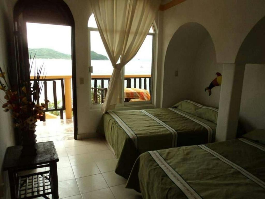 1 dormitorio con 2 camas y balcón en la vista the view en Zihuatanejo