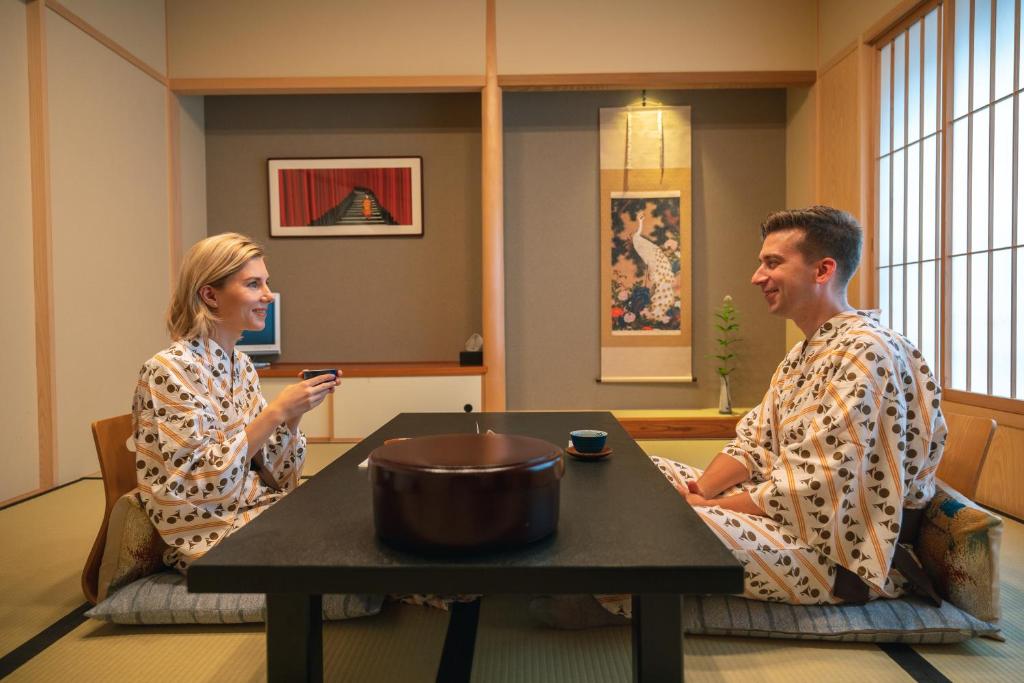 um homem e uma mulher sentados numa mesa numa sala em Nishiyama Ryokan - 1953年創業 em Quioto