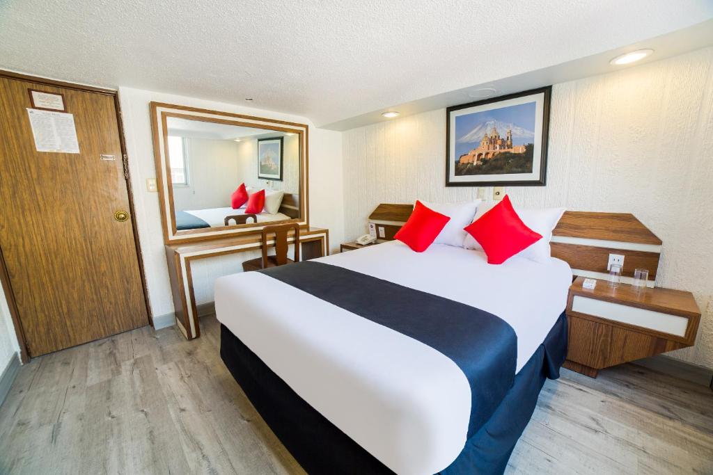 a hotel room with a large bed with red pillows at Hotel Marti in Mexico City