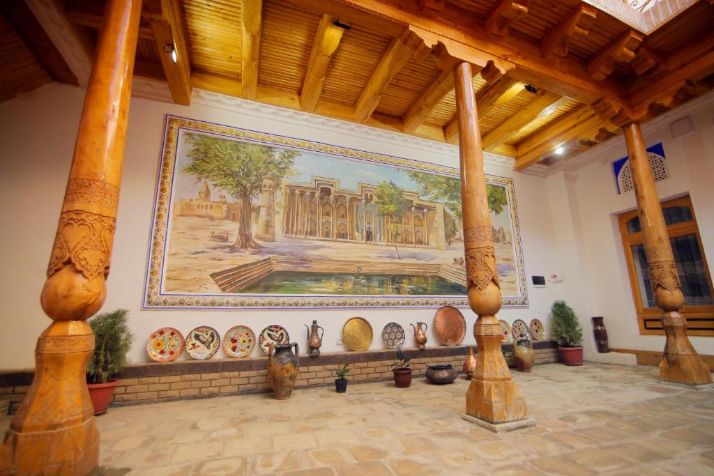 a large painting on the wall in a room with pots at Mukhlisabegim Hotel in Bukhara