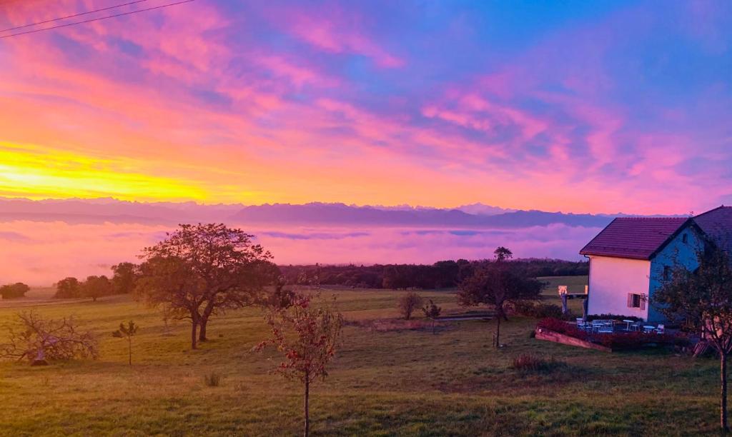 a house in the middle of a field with a sunset at La Ferme de la Praz B&B in La Praz