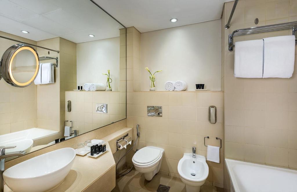 a bathroom with a sink and a toilet and a tub at Metropolitan Al Mafraq Hotel in Abu Dhabi