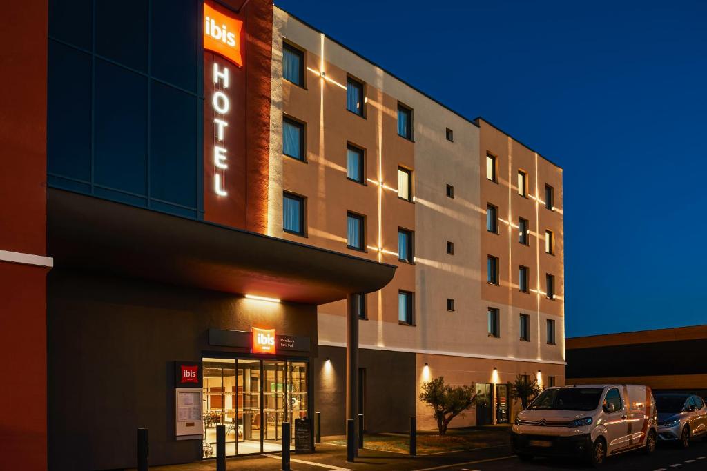 a hotel building with a car parked in front of it at Ibis Montlhery Paris Sud in Montlhéry