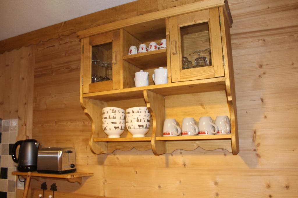a kitchen with wooden cabinets and cups and a toaster at L'Enclave in Les Contamines-Montjoie