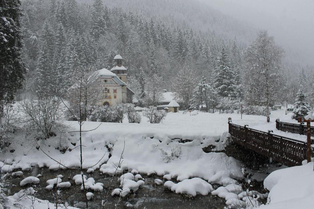 a snow covered yard with a house and a river at L'Enclave in Les Contamines-Montjoie