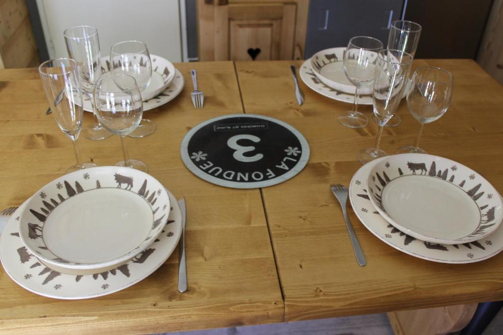a wooden table with plates and wine glasses on it at L'Enclave in Les Contamines-Montjoie